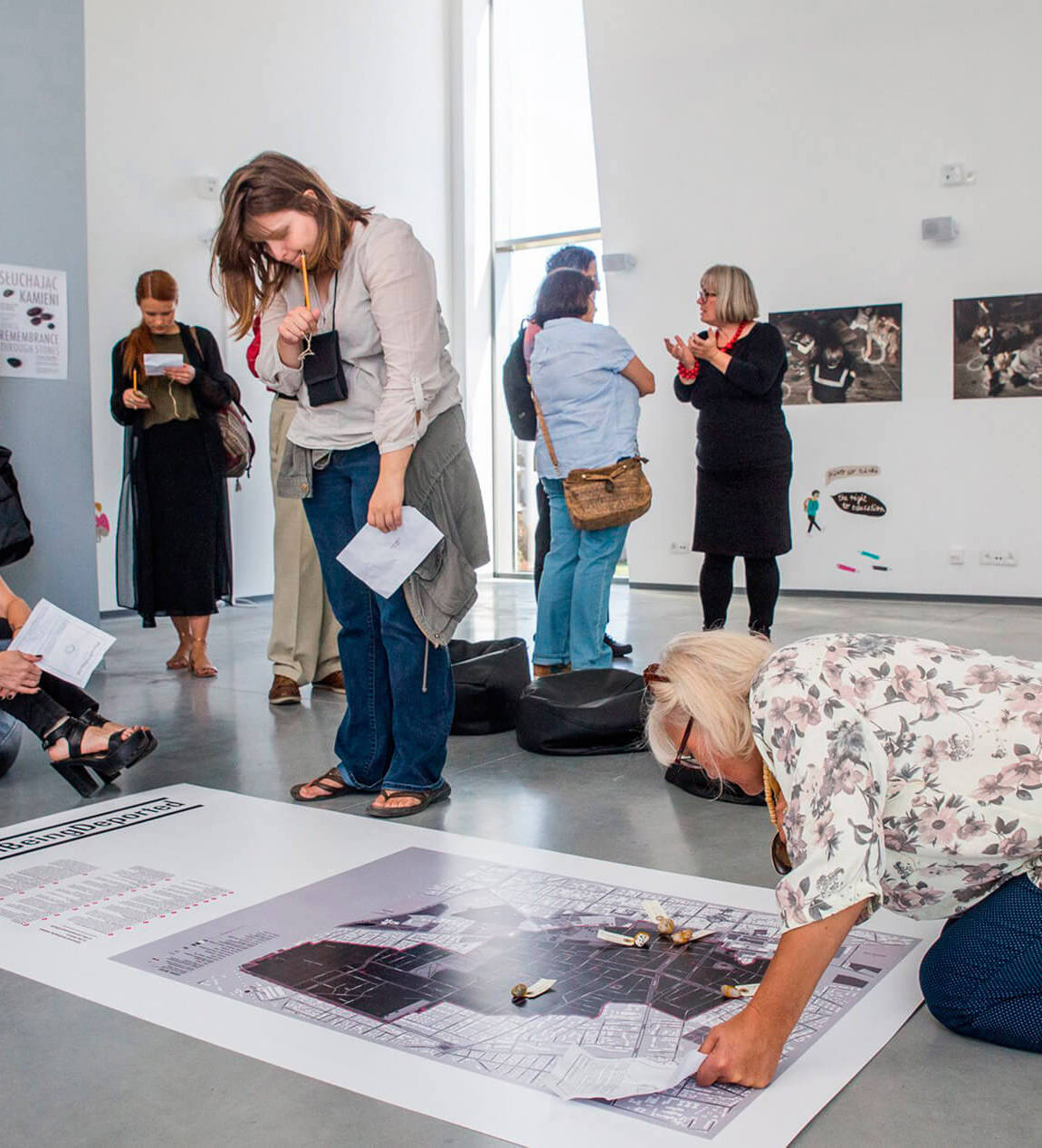 People at a workshop discussing the work with the artist and observing a map on the floor