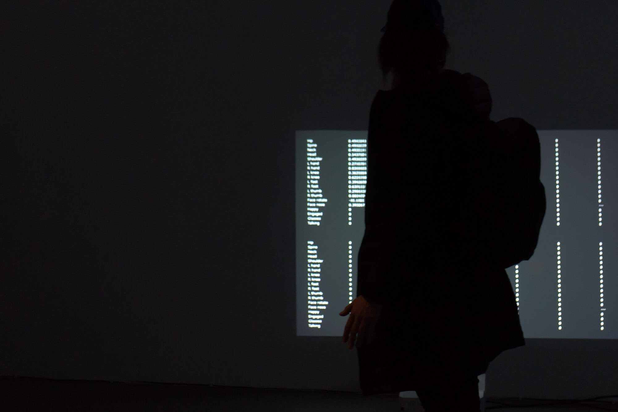 A person in a dark room observing the numbers projected on a wall